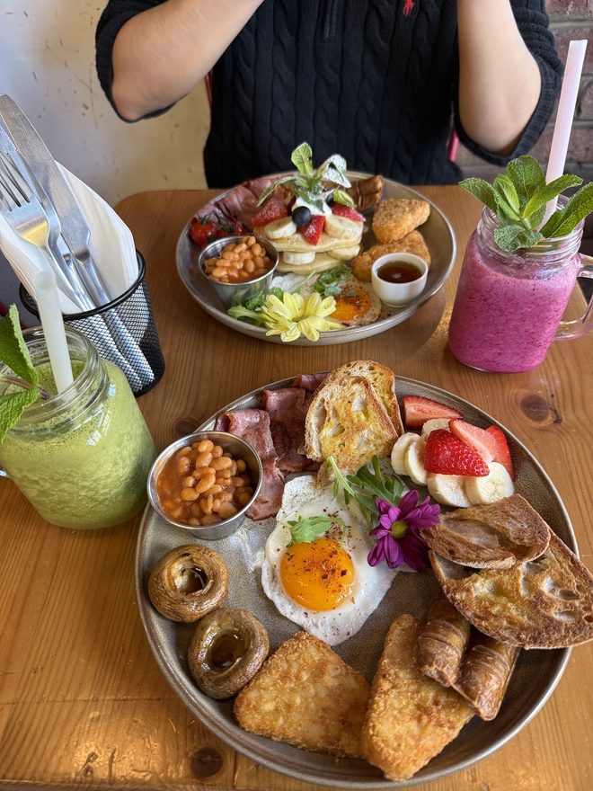 Two loaded sharing platters with waffles, eggs and hash browns and two smoothies