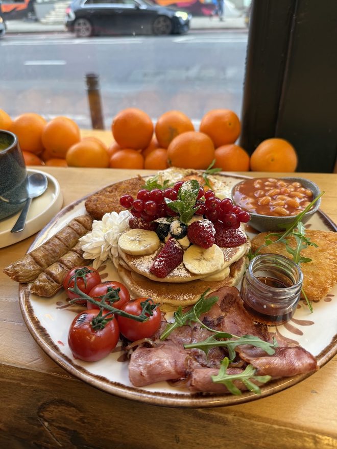 A big brunch board with a crate of oranges behind it by the window