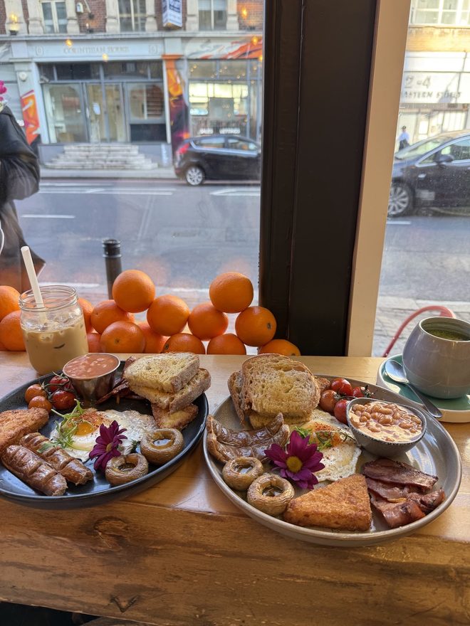 Breakfast platters on a wooden table at the front window looking onto Great Eastern Street