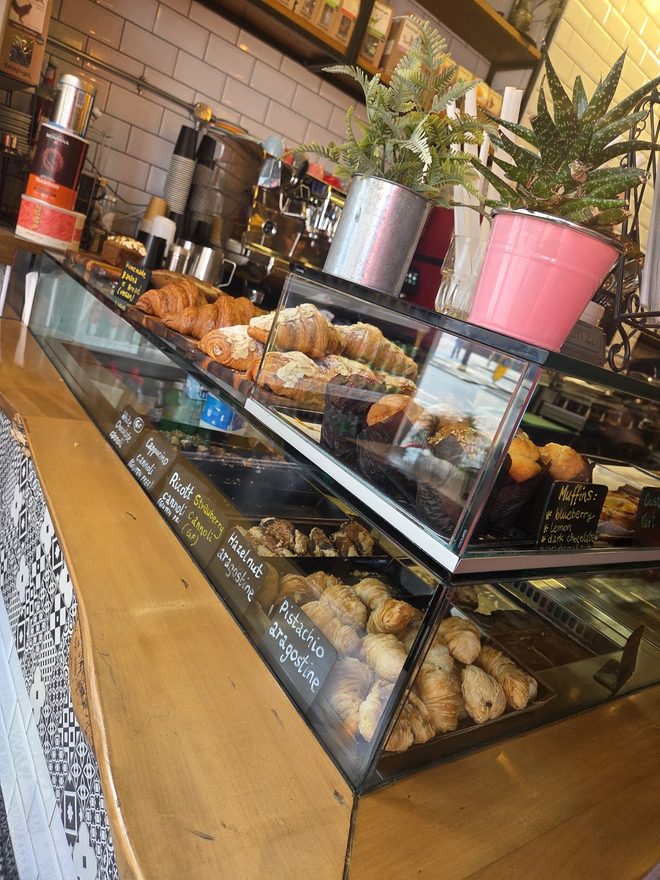 The glass pastry counter stacked with croissants against white metro tiles