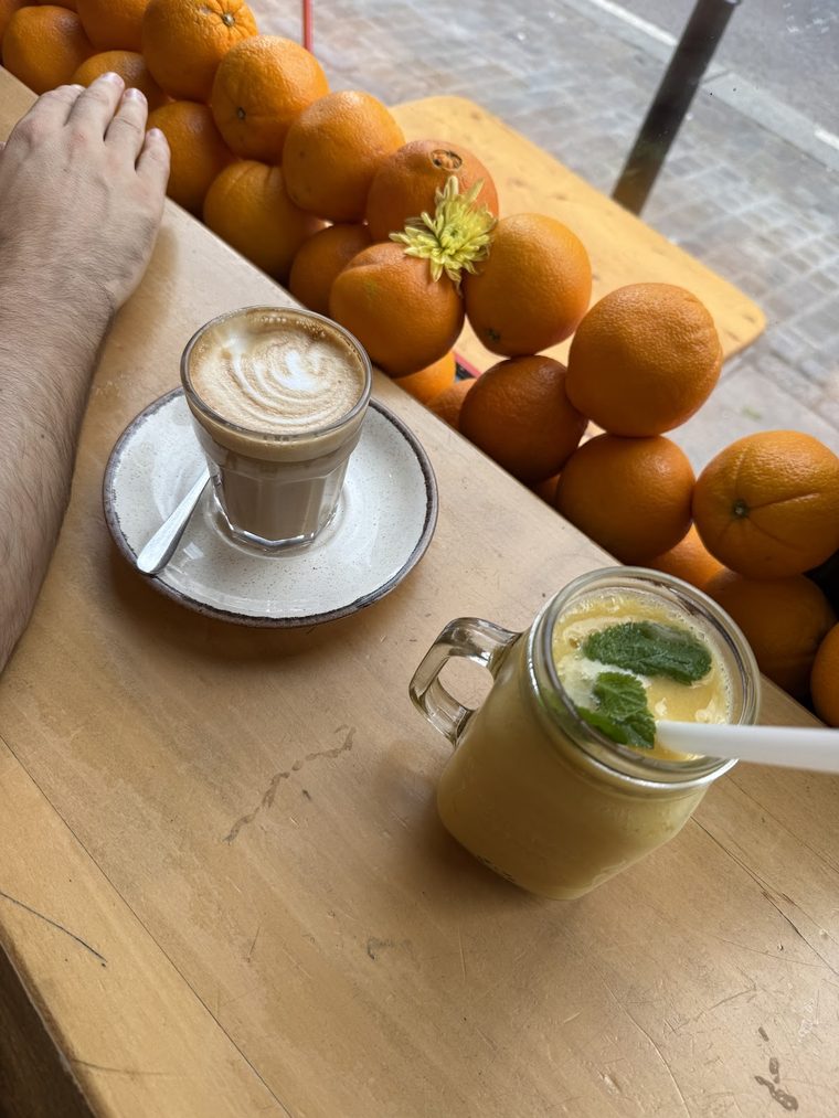 A latte in a glass beside a jar of green juice