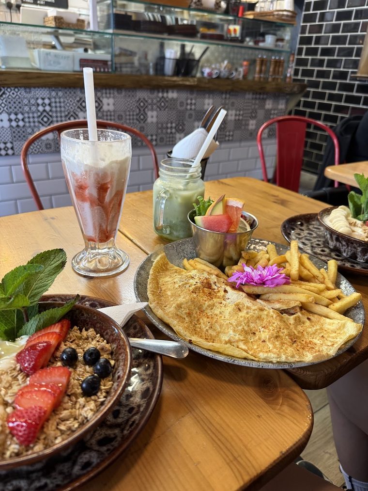 An omelette with fries, a berry and granola bowl and a tall milkshake